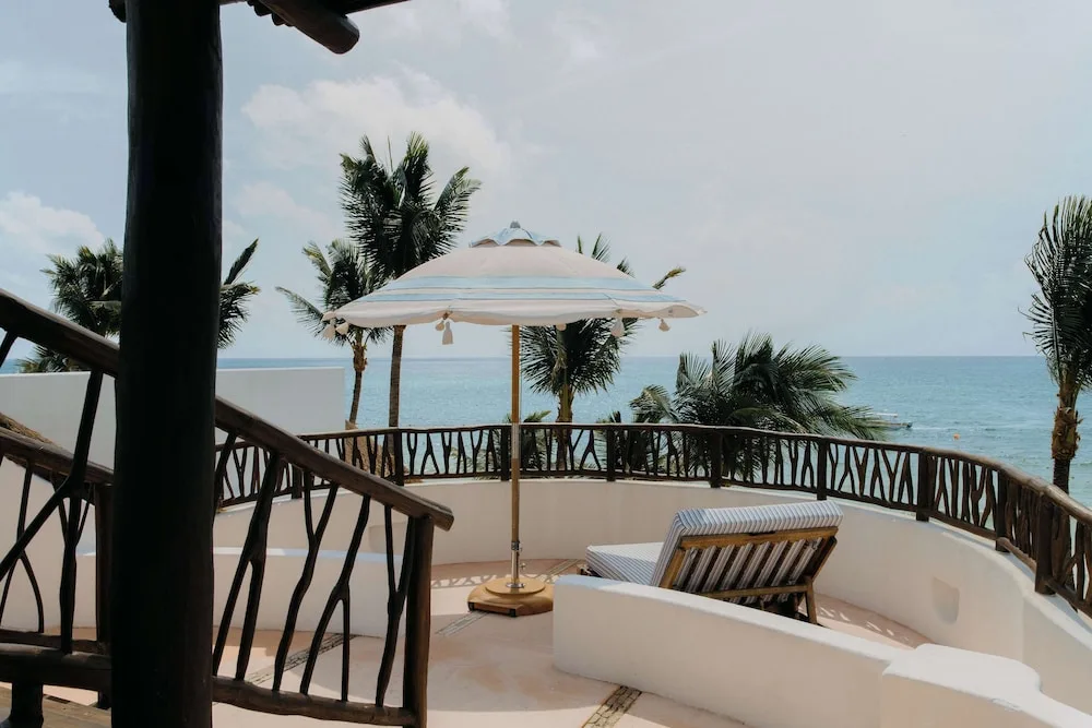 Private terrace with umbrella, lounger, palms, and sea view at Maroma, Riviera Maya.