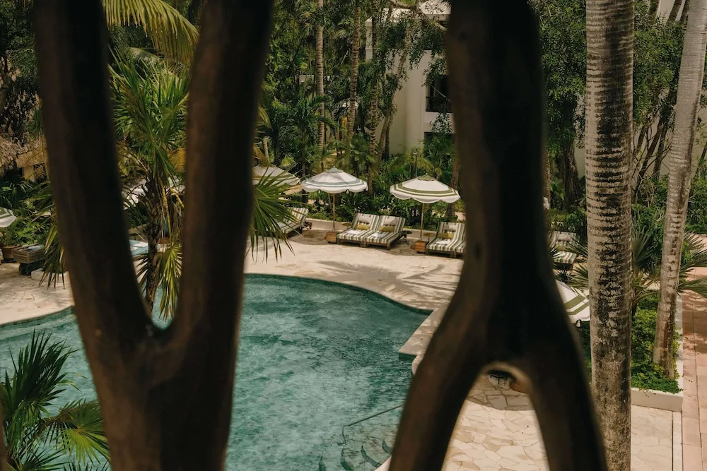 Palm-framed pool with loungers and umbrellas at Maroma, Riviera Maya.