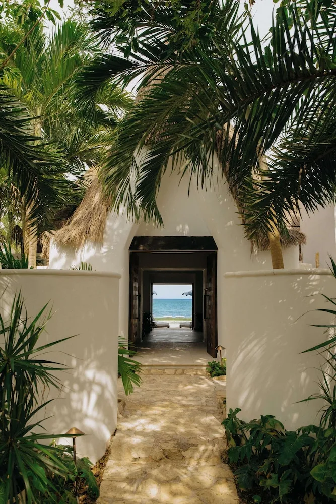 Palm-lined white stucco walkway leading to the ocean at Maroma, Riviera Maya.