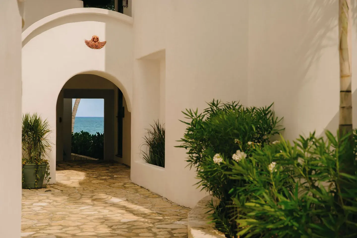 White stucco walkway with an arch framing the sea at Maroma, Riviera Maya.