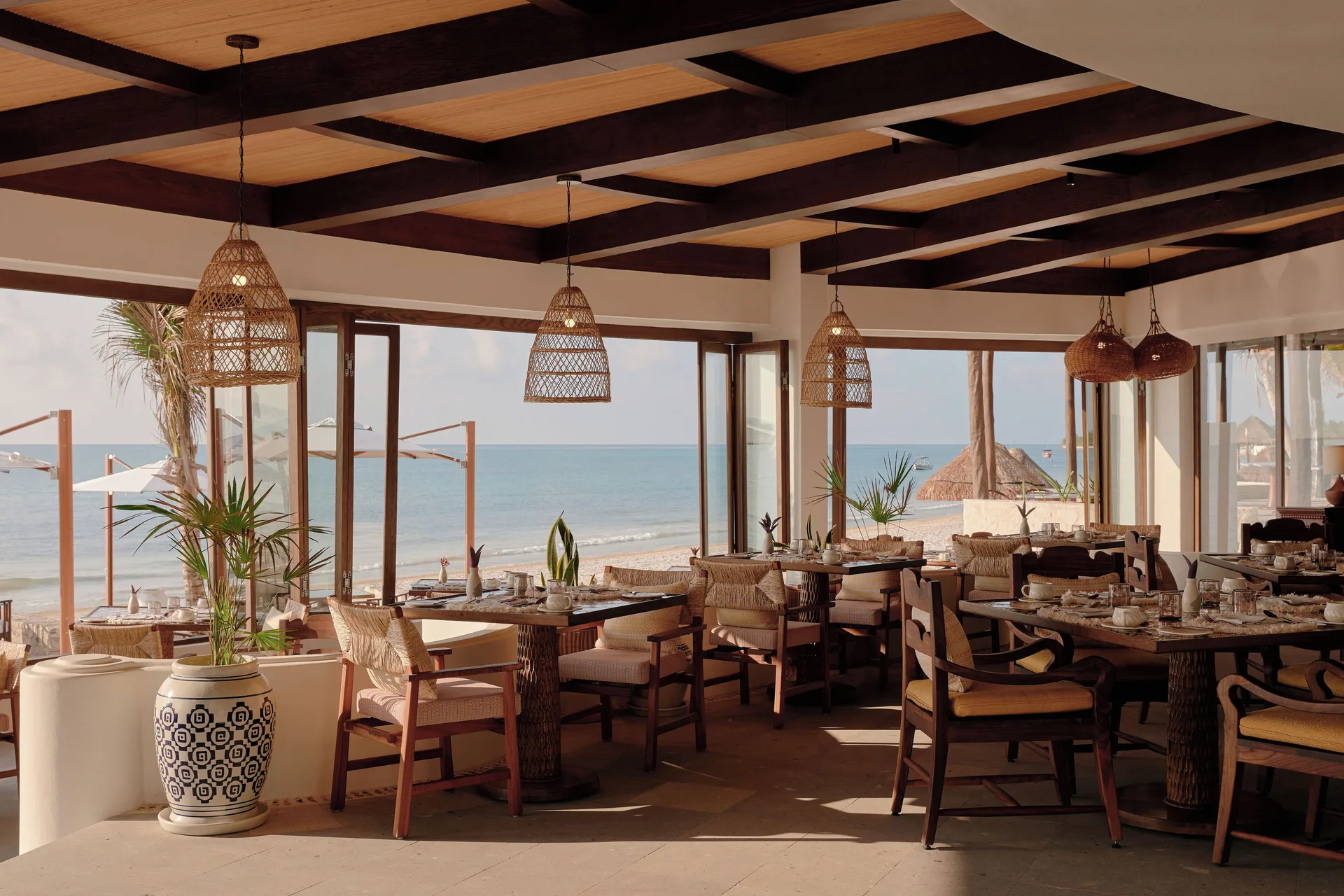 A beachfront dining room with set tables and ocean views at Maroma, Riviera Maya.