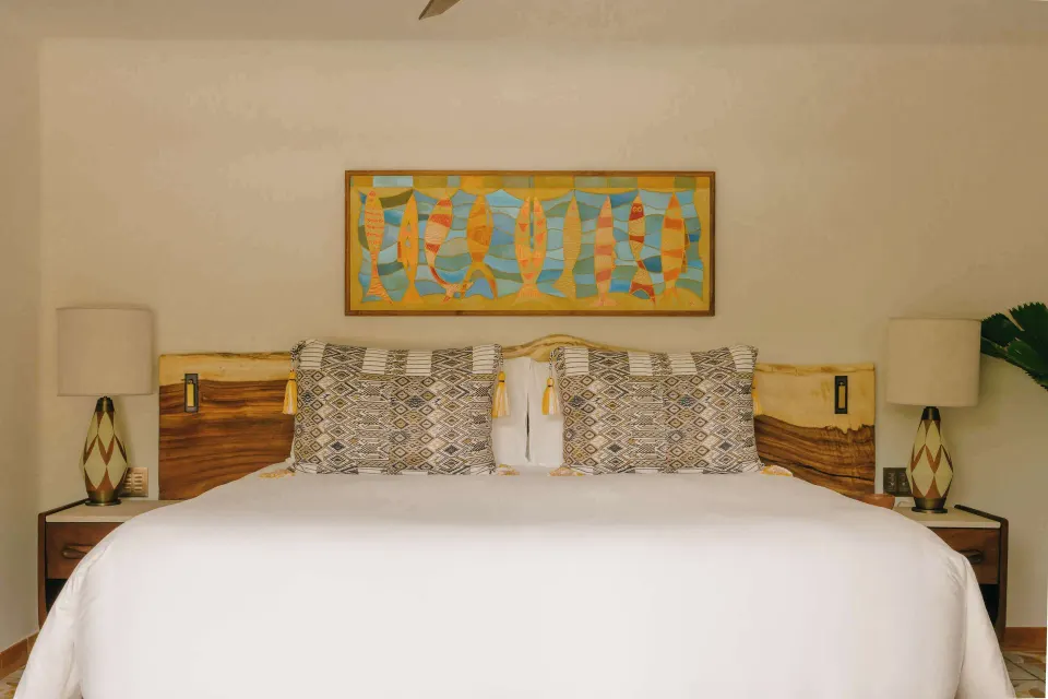 Deluxe Garden View Room king bed with patterned pillows and artwork at Maroma, Riviera Maya.