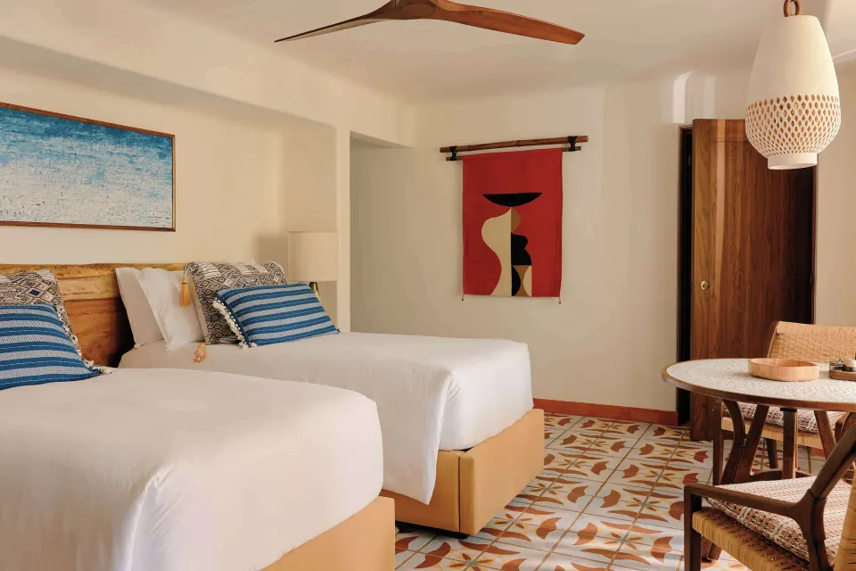 Deluxe Garden View Room with two beds, table, chairs, and wood wardrobe at Maroma, Riviera Maya.