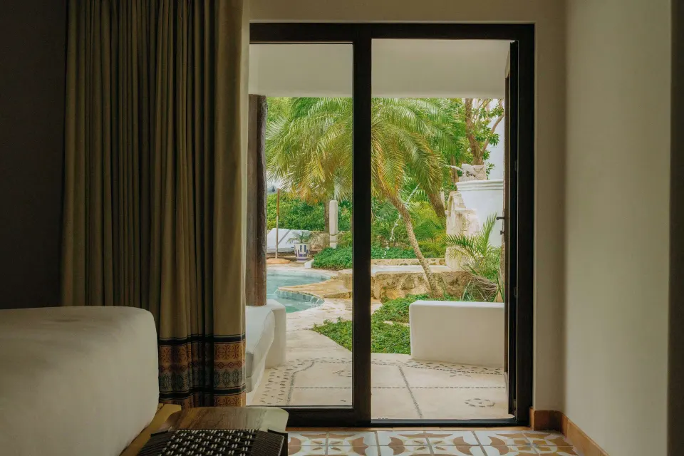 Junior Suite Garden View patio doors open to palms and a plunge pool at Maroma, Riviera Maya.