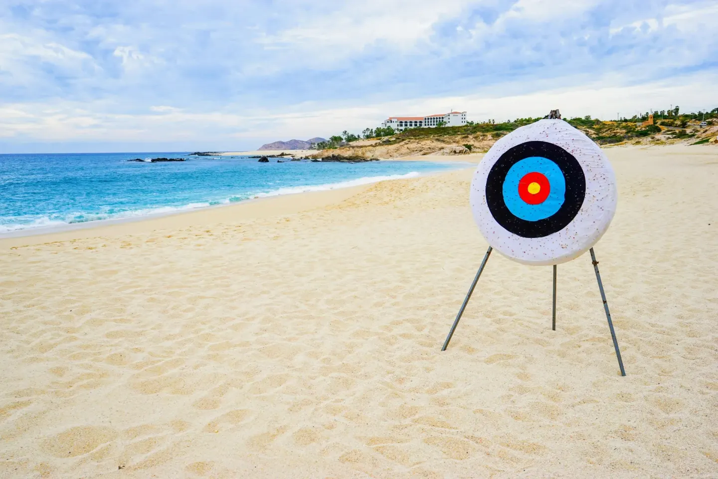 Beach archery target on sand beside blue ocean at Marquis Los Cabos.