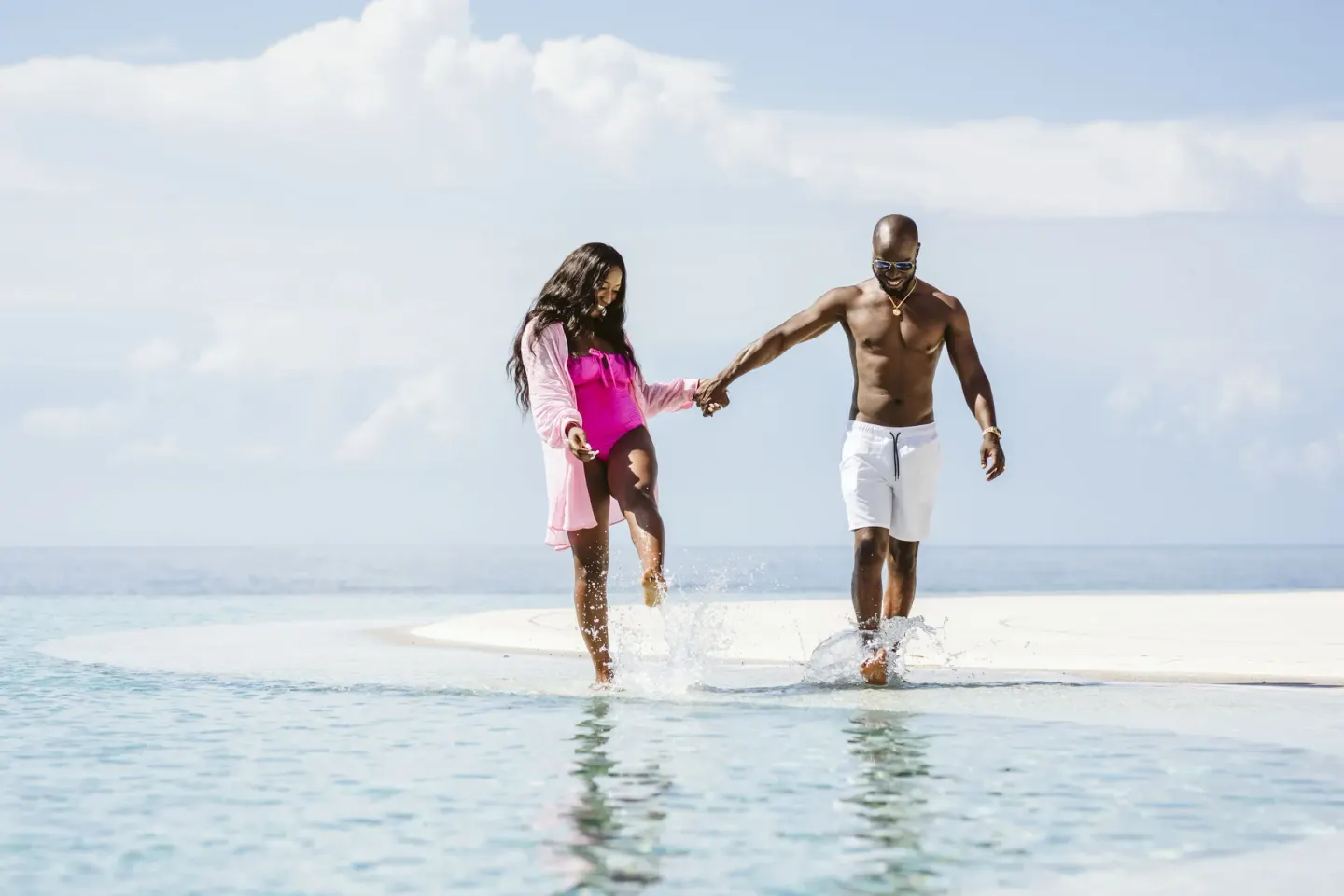 A couple walks through shallow pool water with the ocean behind them at Marquis Los Cabos.