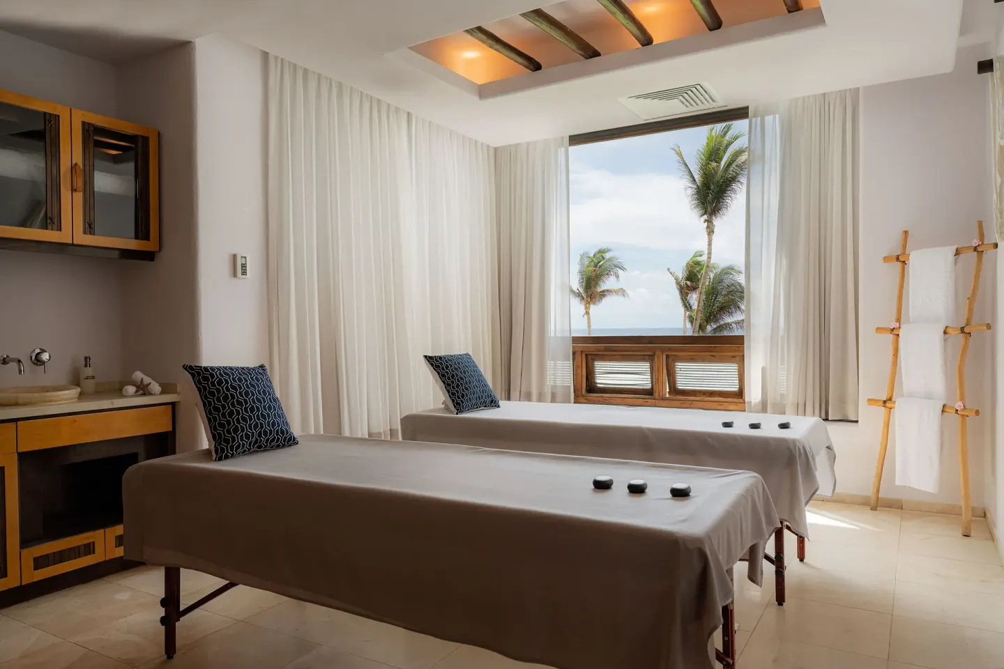 Spa treatment room with two massage tables and an ocean-facing window at Marquis Los Cabos.