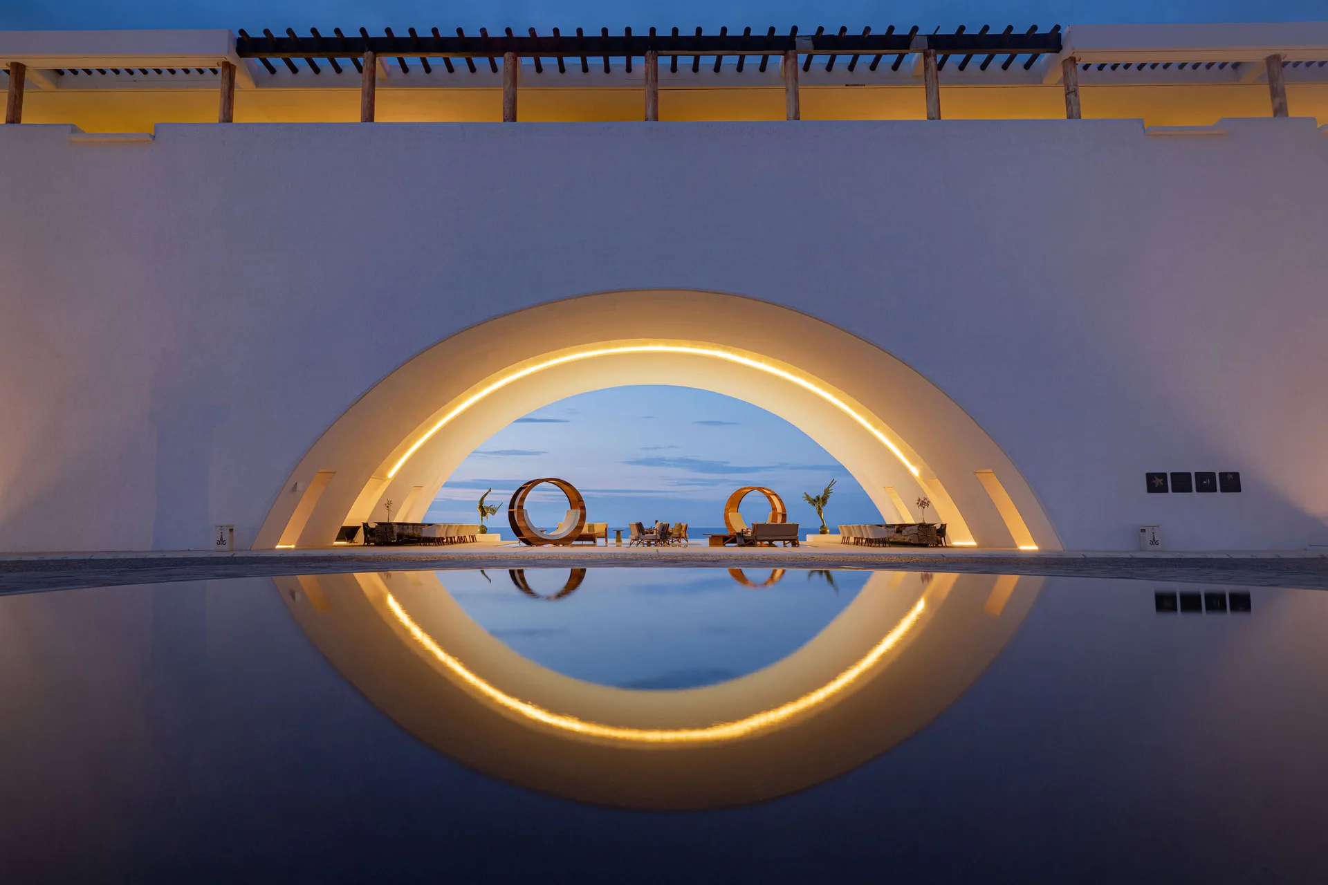 An illuminated arch reflects in a still pool at Marquis Los Cabos.