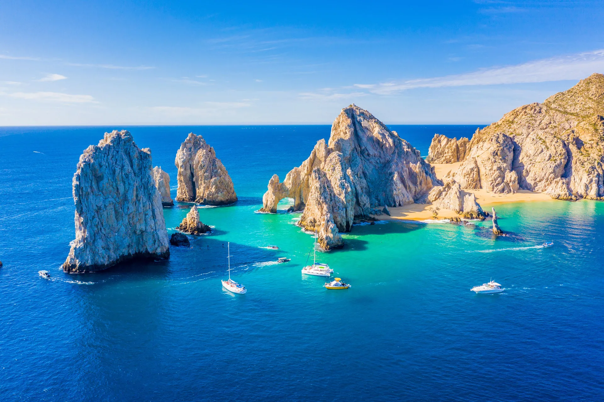 Rock arches, turquoise water, and boats off the coast near Marquis Los Cabos.