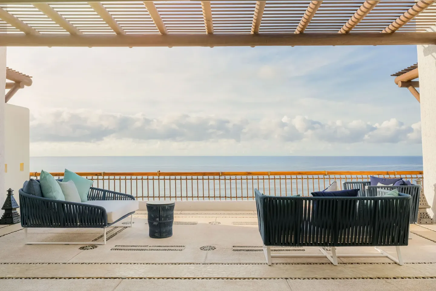 Ocean-view terrace with two cushioned outdoor sofas under a pergola at Marquis Los Cabos.