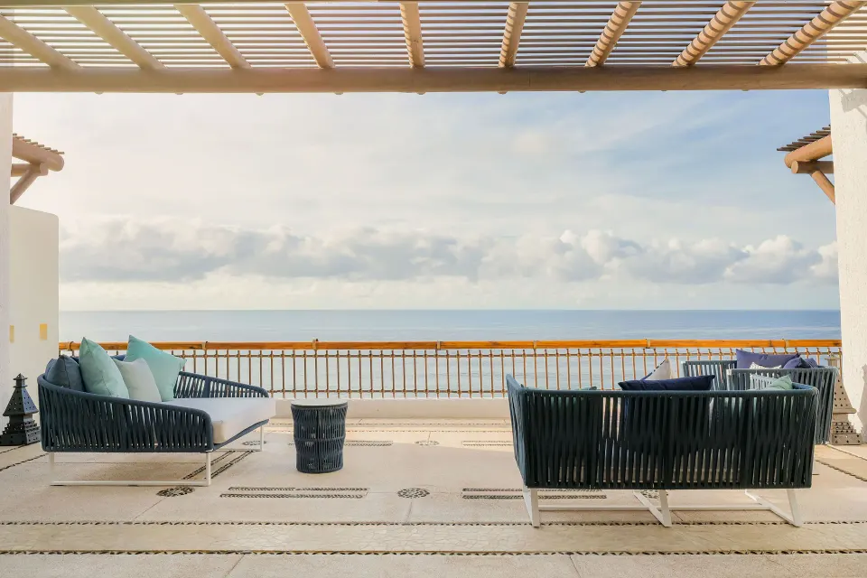 Ocean-view terrace with two cushioned outdoor sofas under a pergola at Marquis Los Cabos.