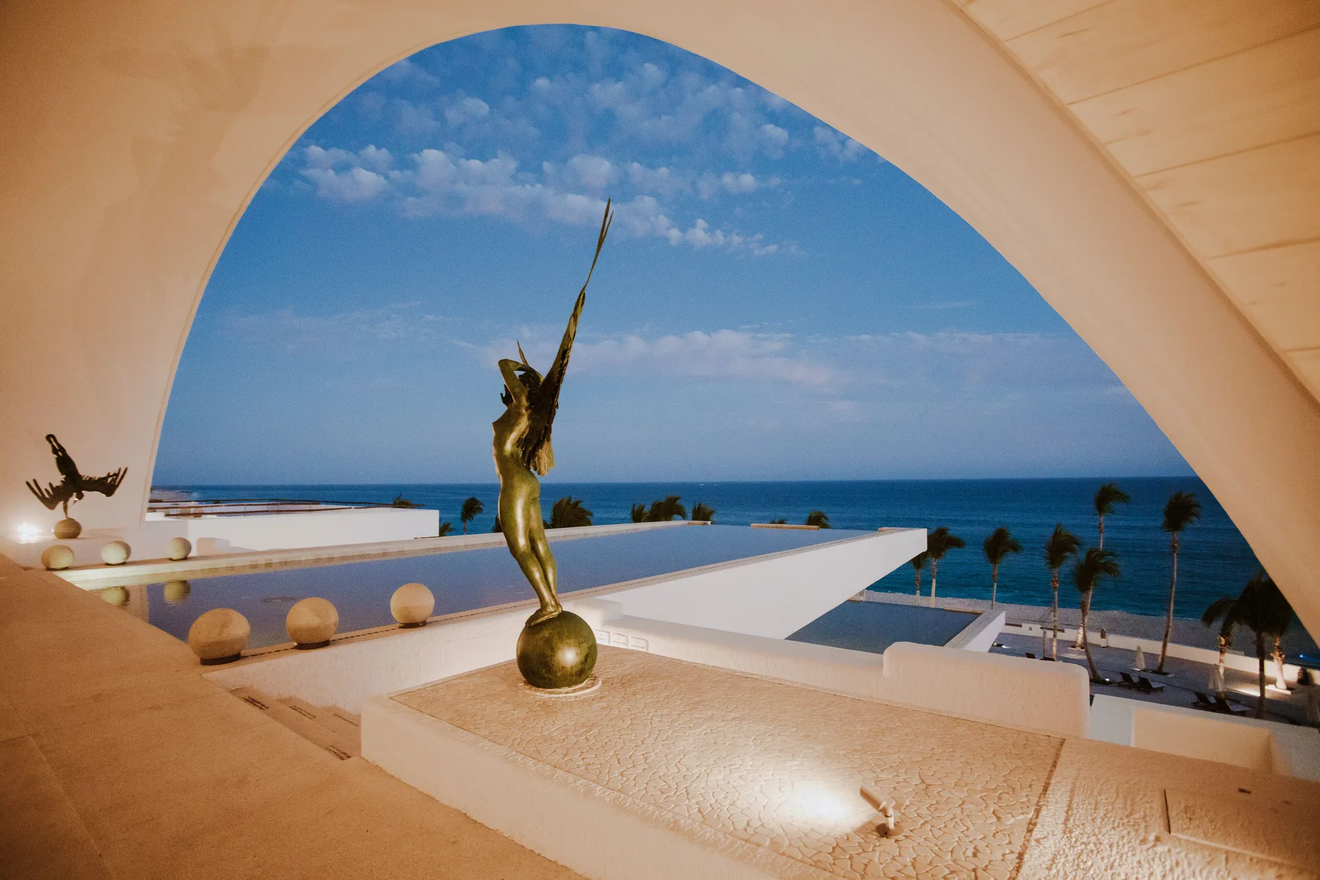 A bronze sculpture stands beneath a large oceanfront arch at Marquis Los Cabos.