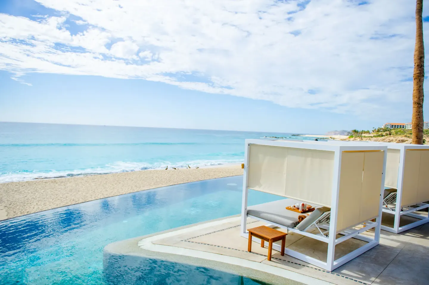 A white pool cabana overlooks the beach and ocean at Marquis Los Cabos.