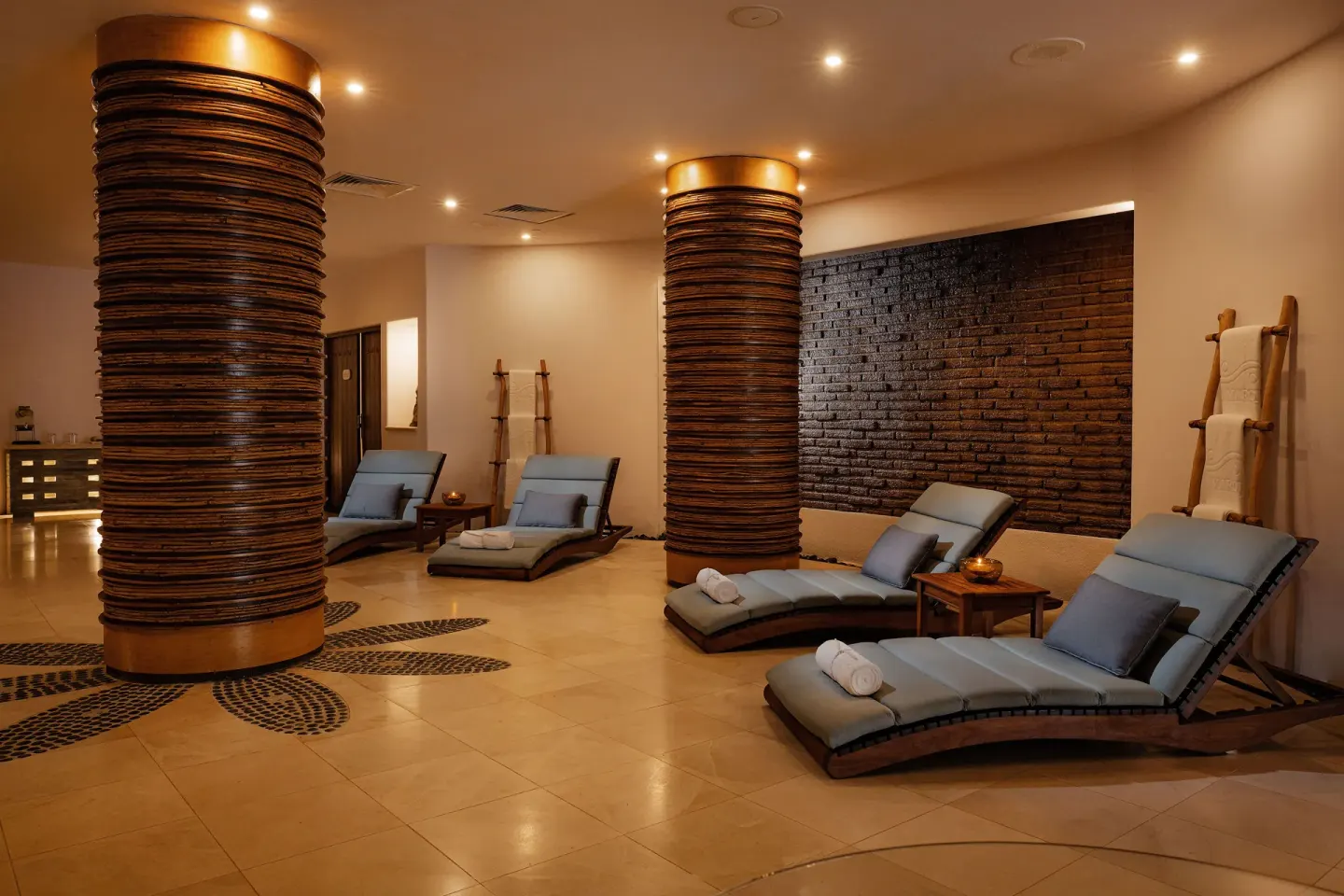 Spa relaxation room with cushioned loungers and textured columns at Marquis Los Cabos.