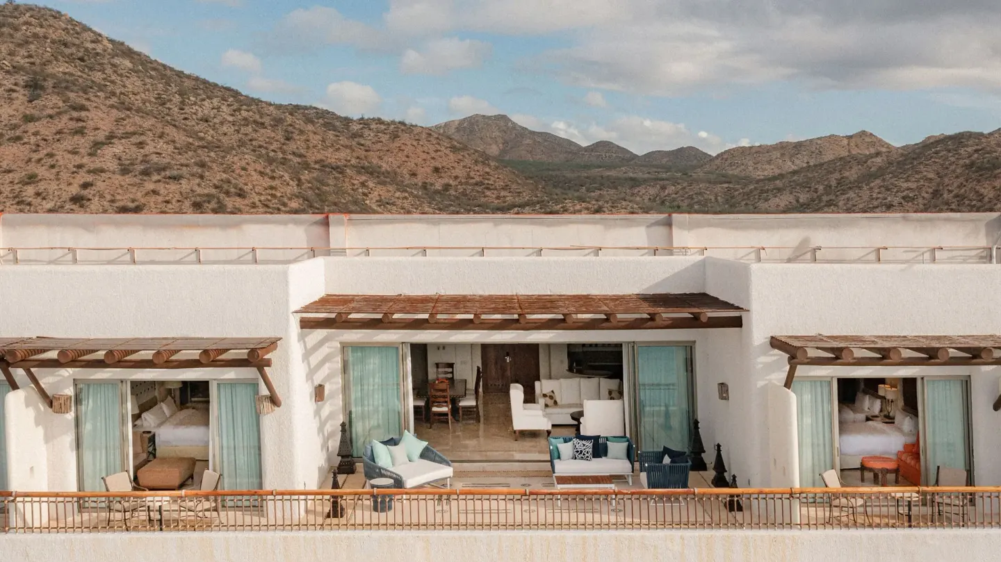 Exterior view of suite terraces and open rooms against desert hills at Marquis Los Cabos.