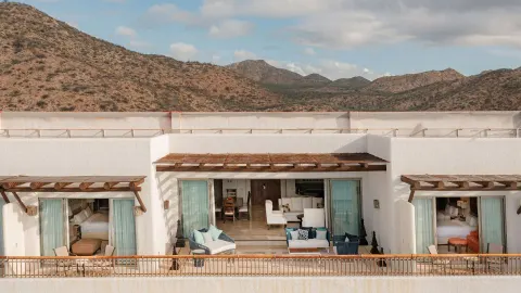 Exterior view of suite terraces and open rooms against desert hills at Marquis Los Cabos.