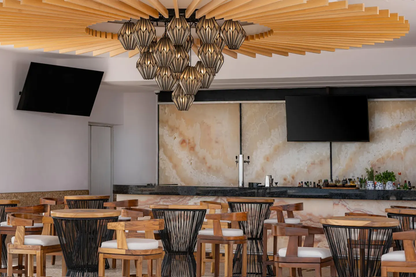 Indoor bar seating with wood chairs and pendant lights at Marquis Los Cabos.