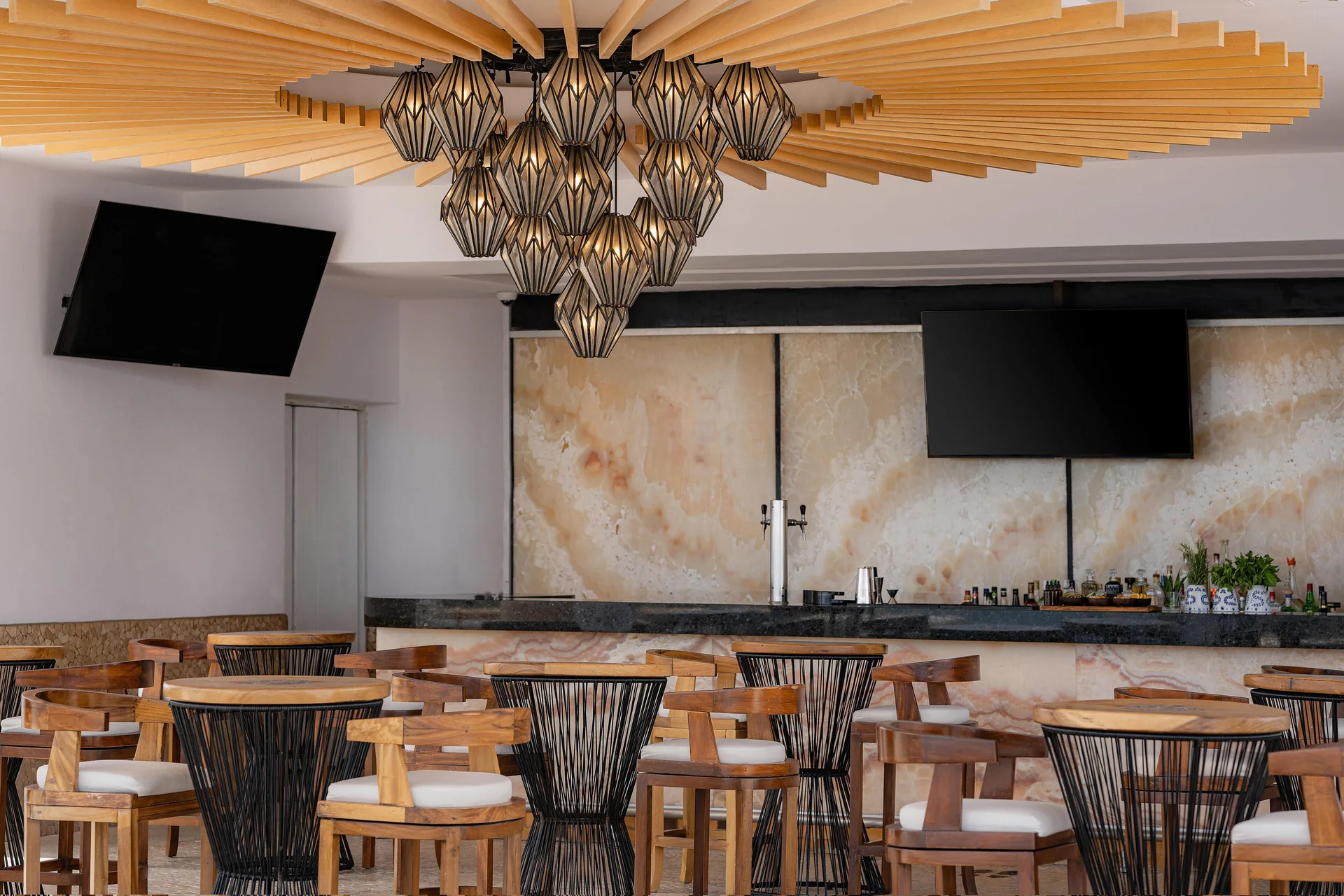 Indoor bar seating with wood chairs and pendant lights at Marquis Los Cabos.