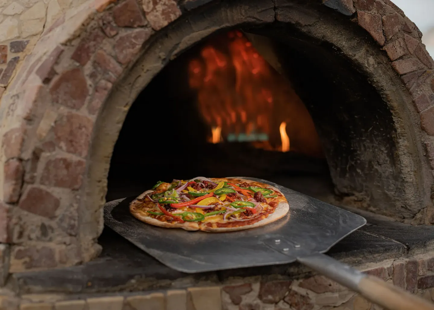A pizza on a peel is shown at a wood-fired oven at Marquis Los Cabos.