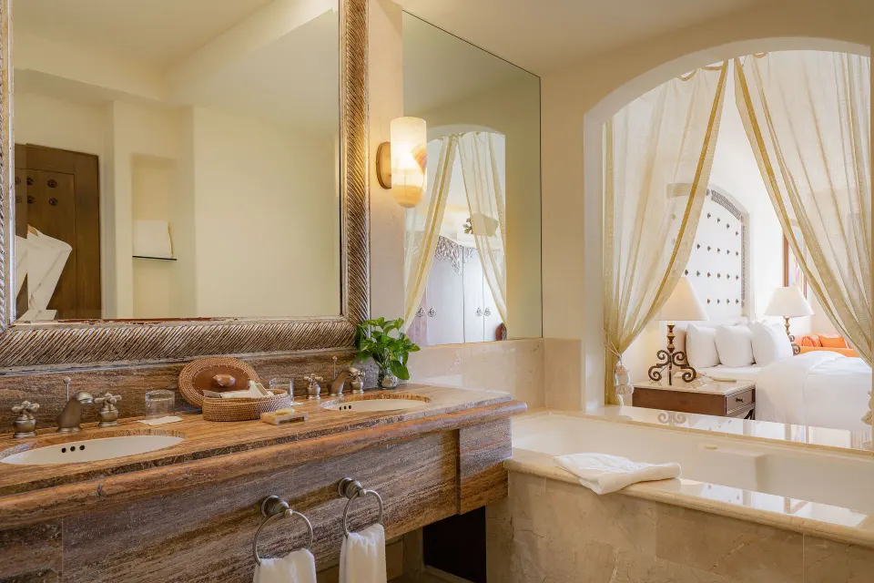 Junior Suite Ocean View bathroom with tub and bedroom beyond at Marquis Los Cabos.