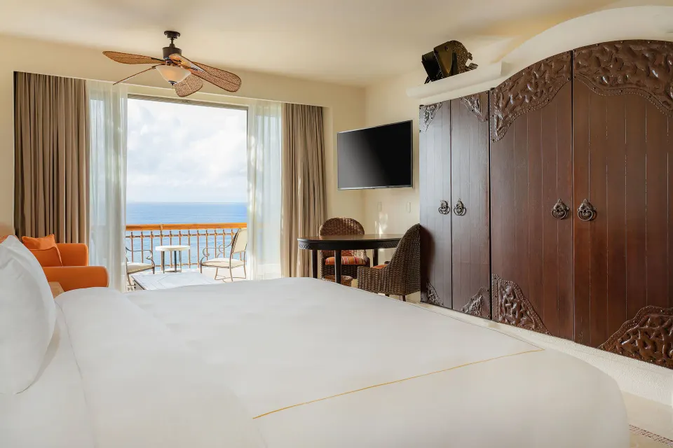 Junior Suite Ocean View at Marquis Los Cabos with king bed, balcony, TV and carved wardrobe.