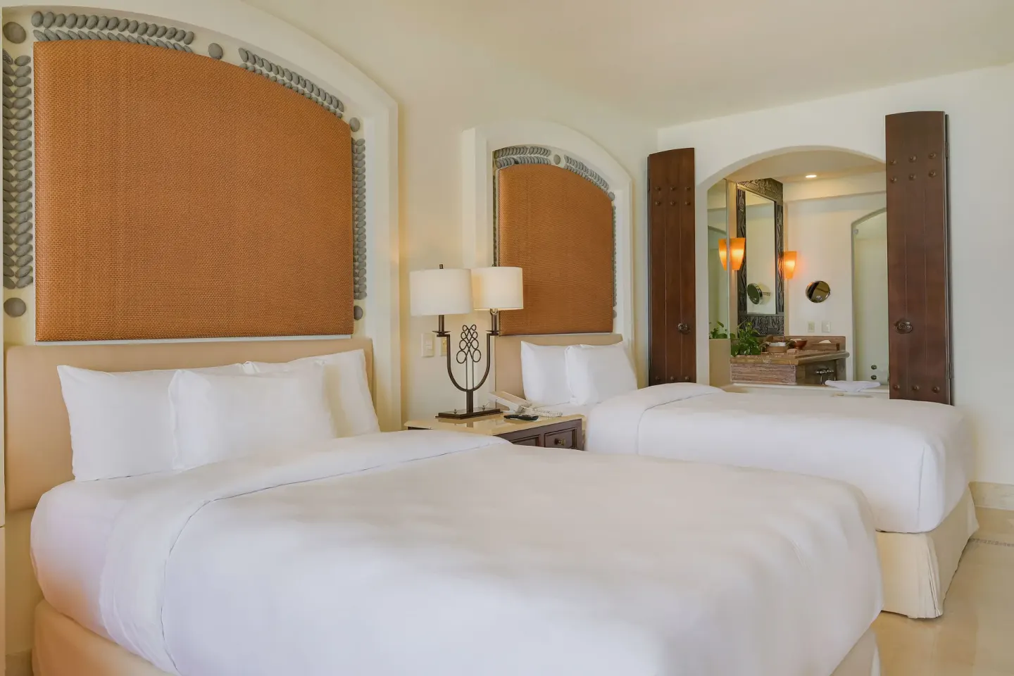 Two beds and an open vanity area in a Junior Suite Ocean View at Marquis Los Cabos.