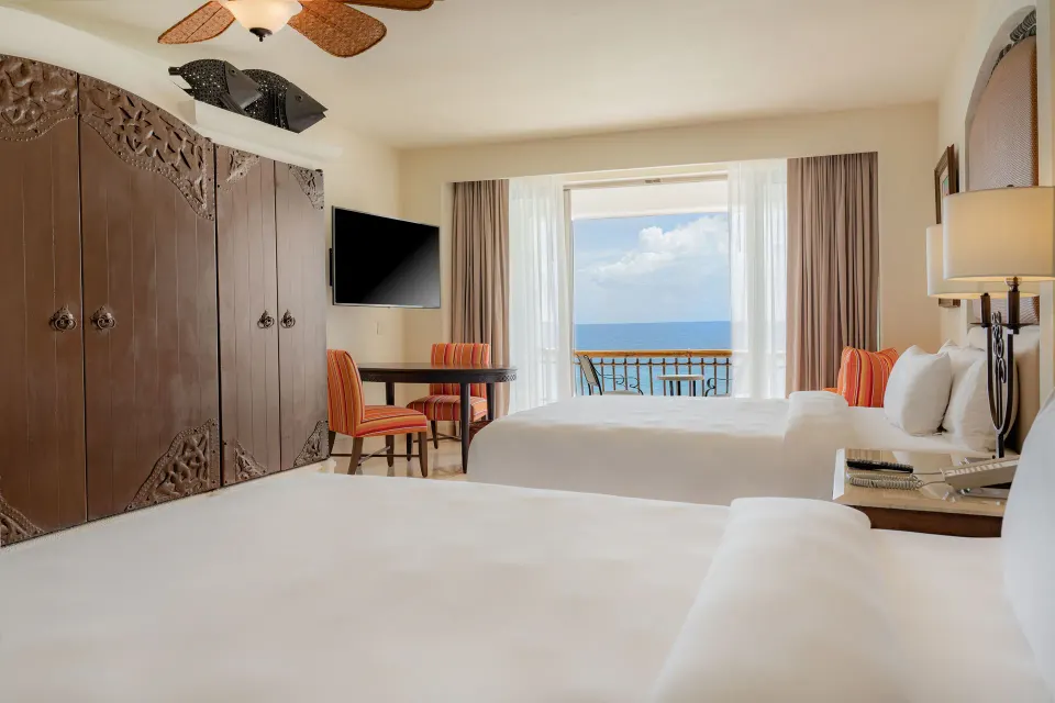 Junior Suite Ocean View at Marquis Los Cabos with two beds, wardrobe, desk, TV and balcony.