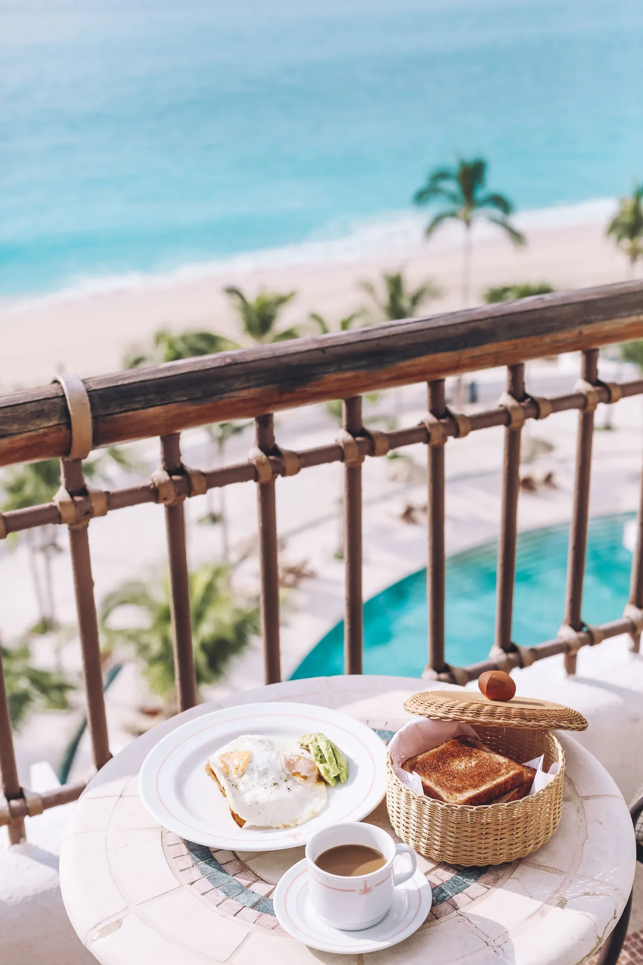 Breakfast on a Junior Suite Oceanfront balcony at Marquis Los Cabos overlooking the beach and pool.