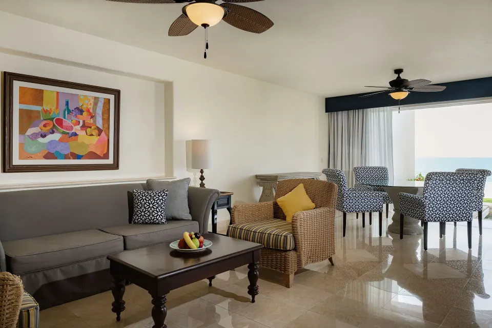 Ocean View Casita living area with sofa, dining table, and ocean glimpse at Marquis Los Cabos.