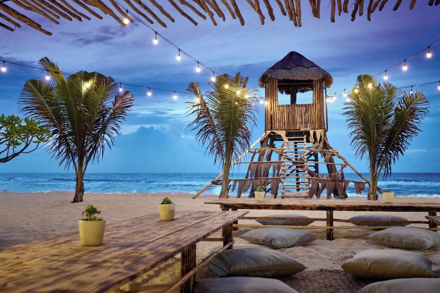 Beach lounge seating and a wooden lookout tower at Marriott Cancun at dusk.