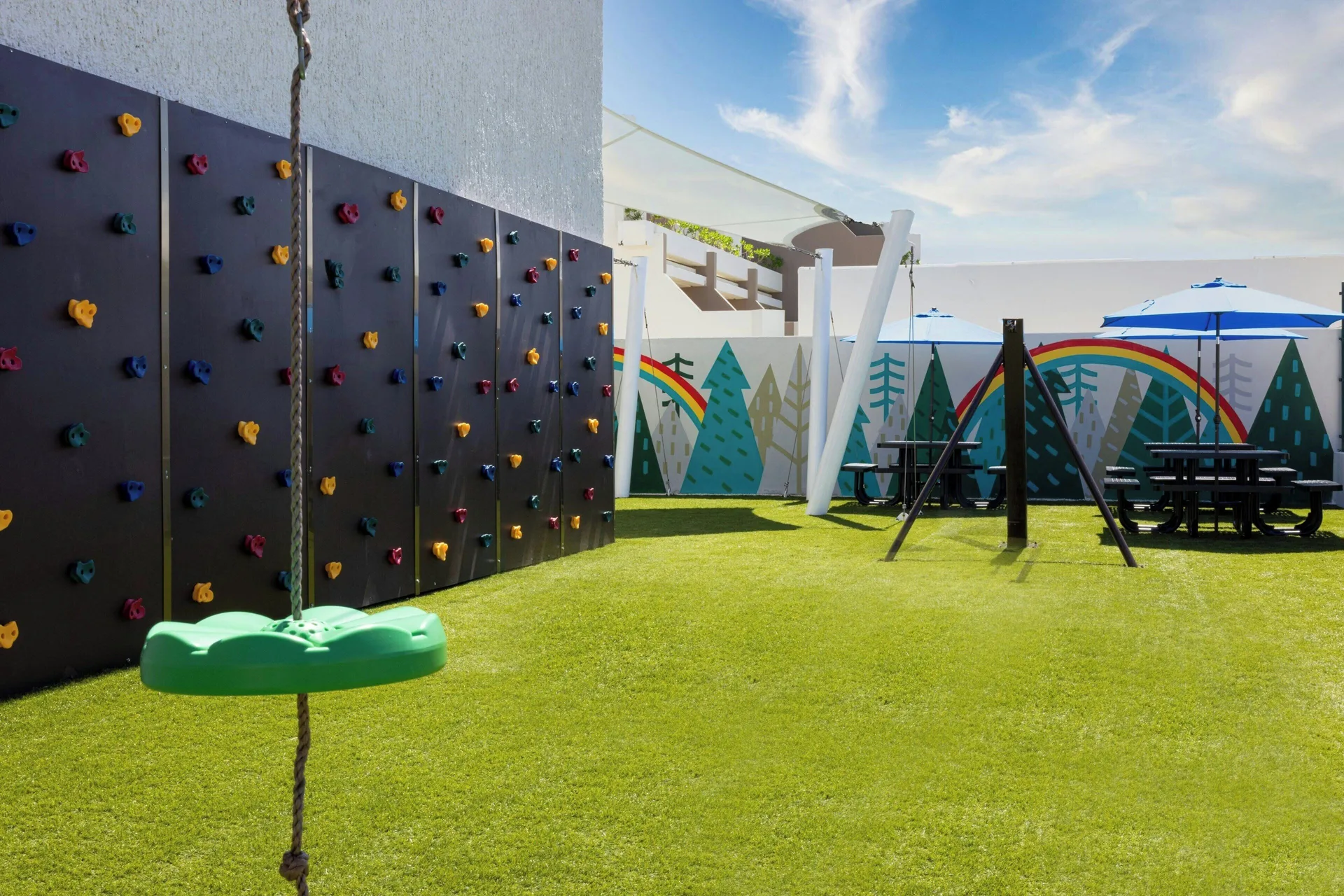 A children’s play area with climbing wall, swings, and picnic tables at Marriott Cancun.