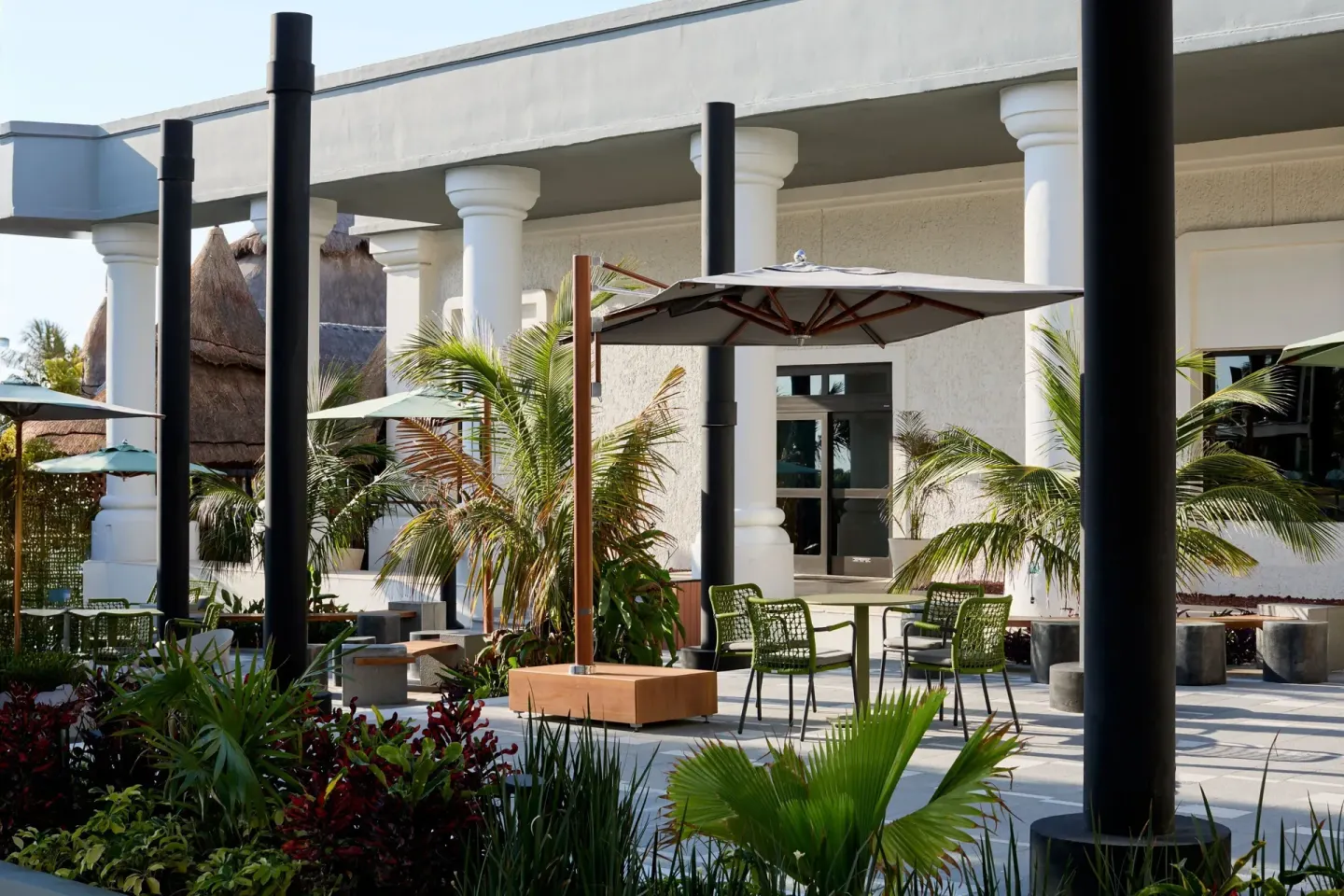 Garden patio with umbrellas, palms, and café tables at Marriott Cancun.