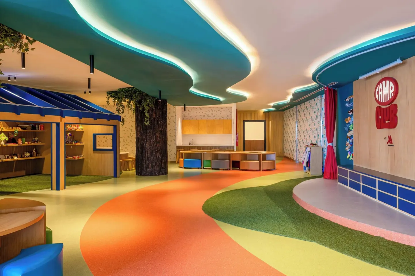 Wide view of kids' club with stage sign, winding floor path, and play areas at Marriott Cancun.