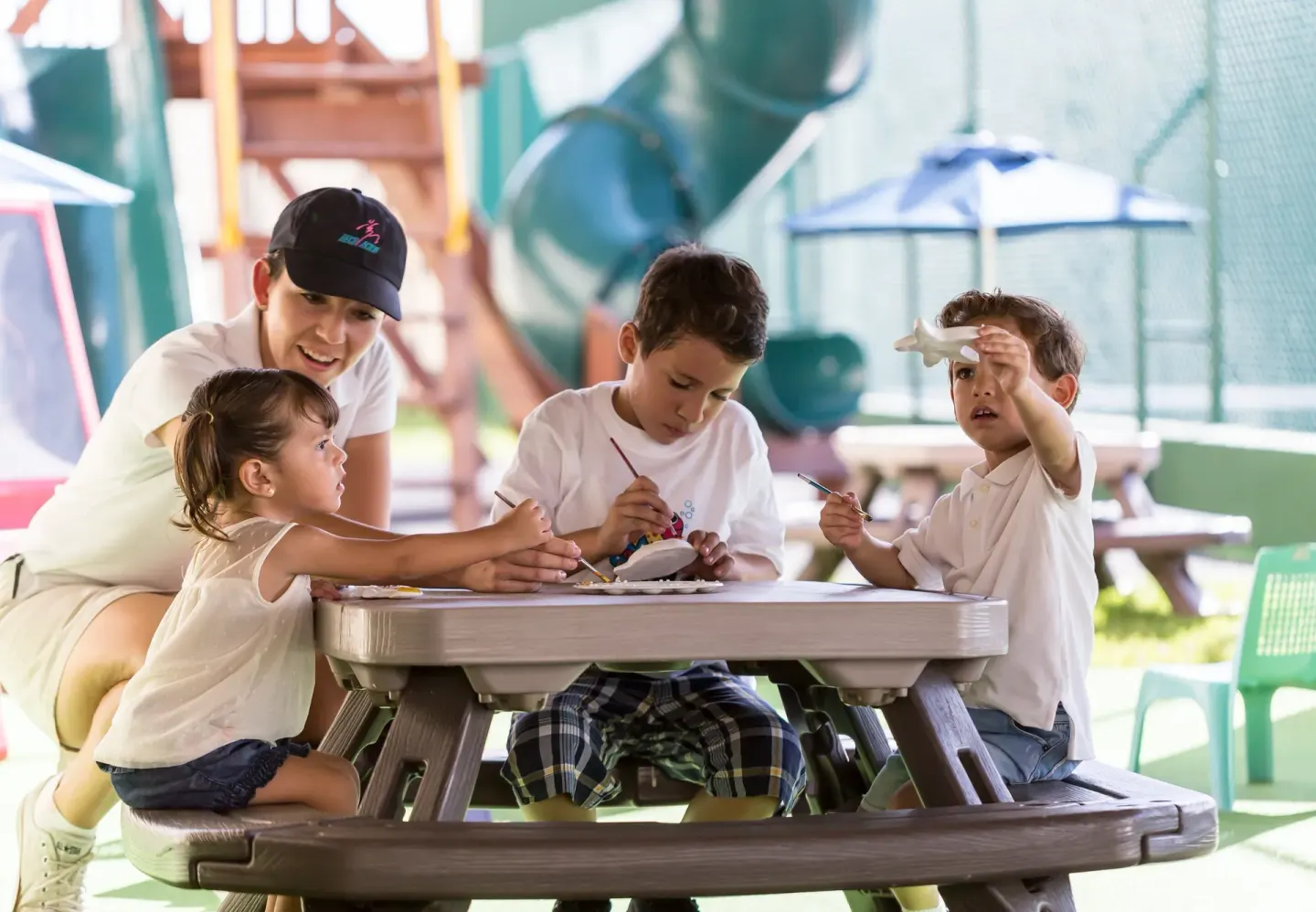 Children paint crafts with a counselor in the kids' play area at Marriott Cancun.