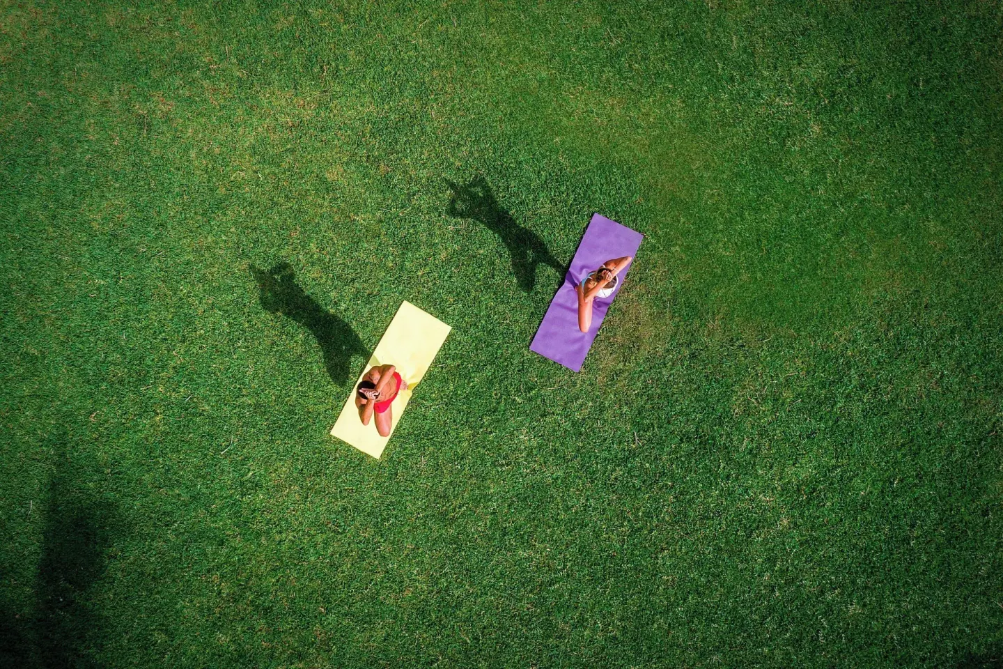 Two people practice yoga on colorful mats on the lawn at Marriott Cancun.