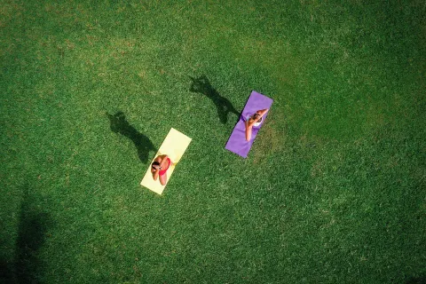 Two people practice yoga on colorful mats on the lawn at Marriott Cancun.