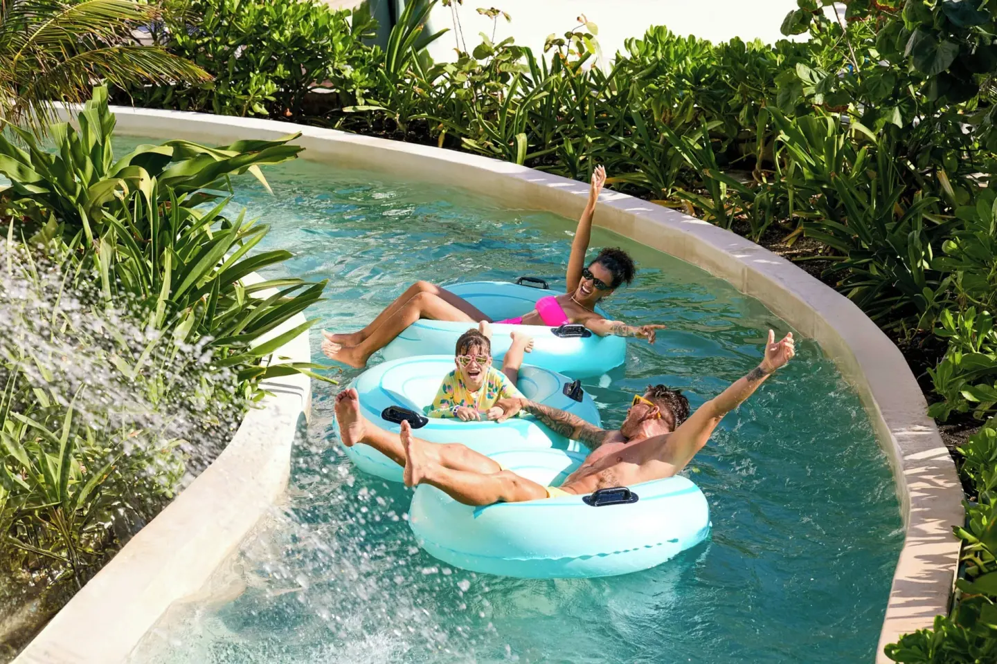 Family floats on blue tubes along a winding water channel at Marriott Cancun.