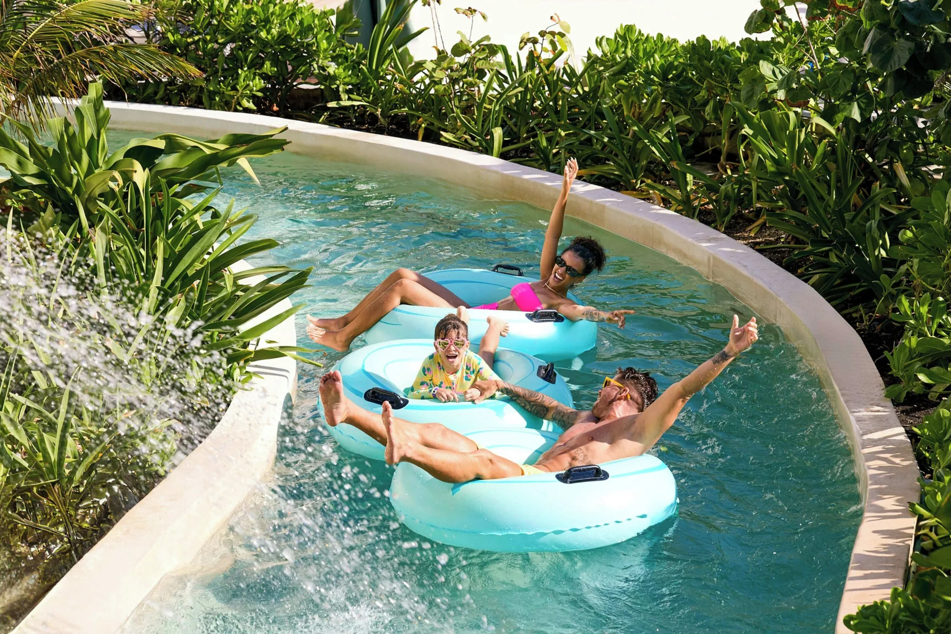 Family floats on blue tubes along a winding water channel at Marriott Cancun.