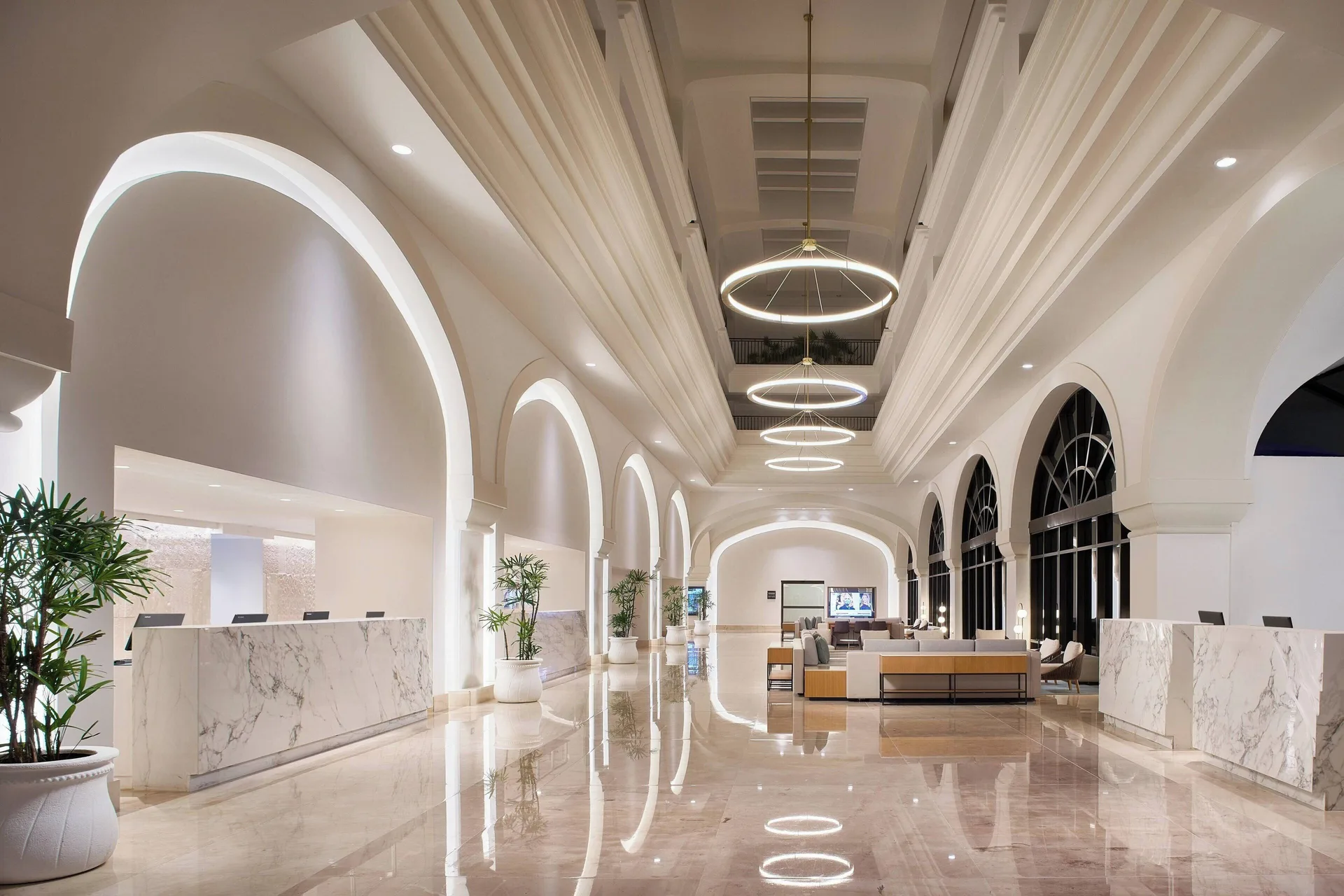 Bright lobby hall with reception desks, arches and lounge seating at Marriott Cancun.