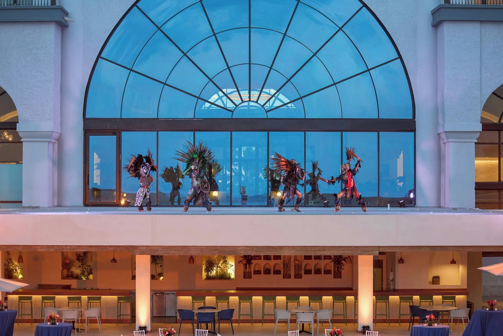 Performers on an outdoor balcony stage above dining tables at Marriott Cancun.