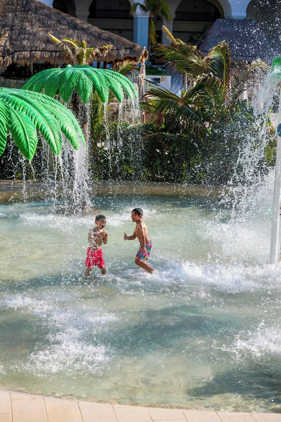 Children play beneath palm-shaped fountains in the splash area at Marriott Cancun.