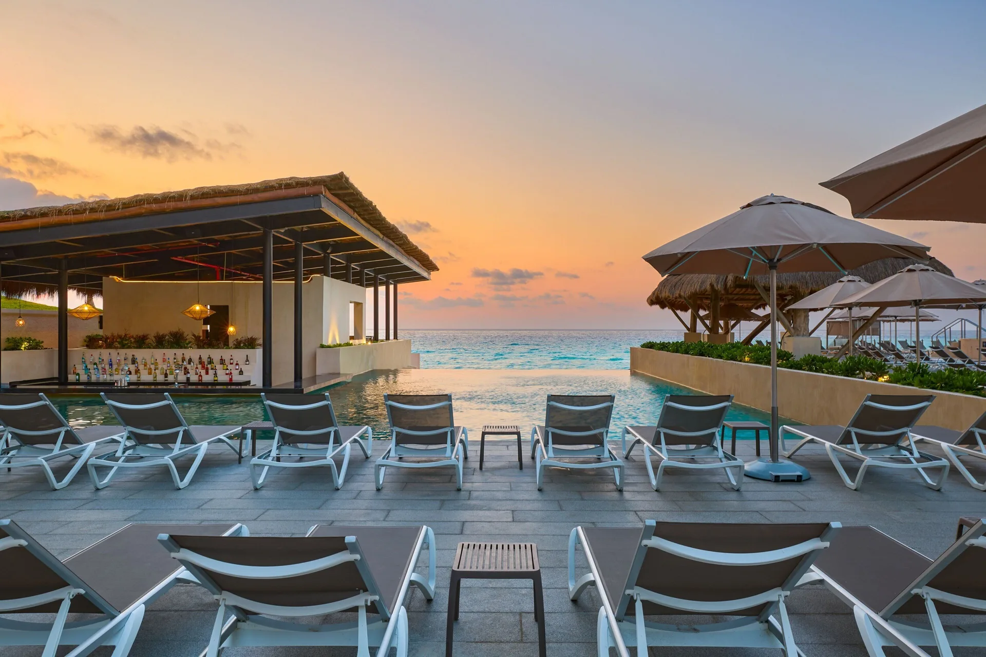 Sunset pool deck with loungers, umbrellas and ocean view at Marriott Cancun.