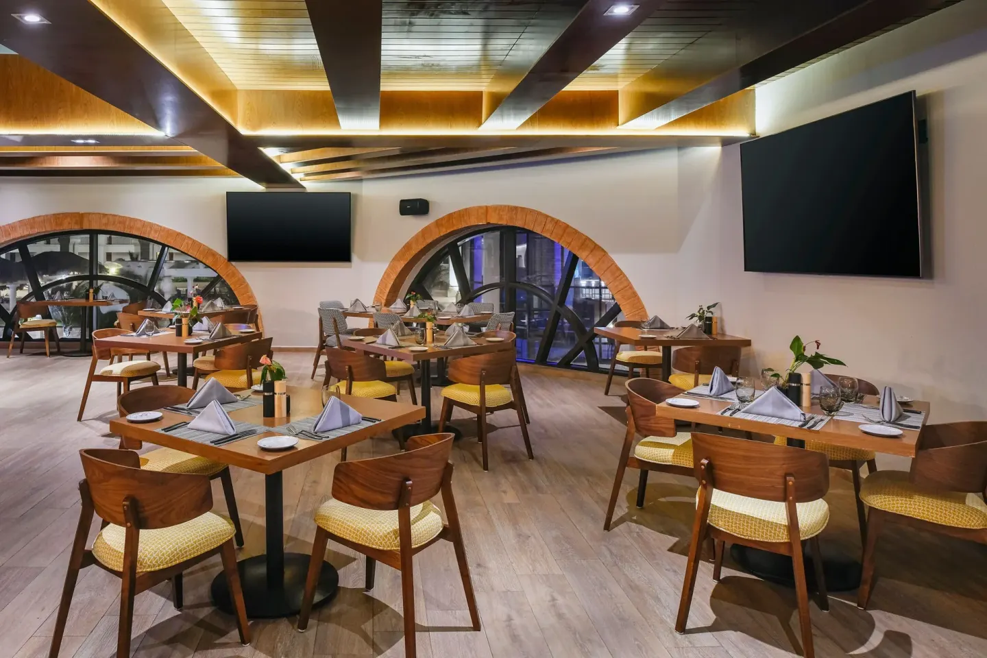 Indoor restaurant with arched windows and set tables at Marriott Cancun.