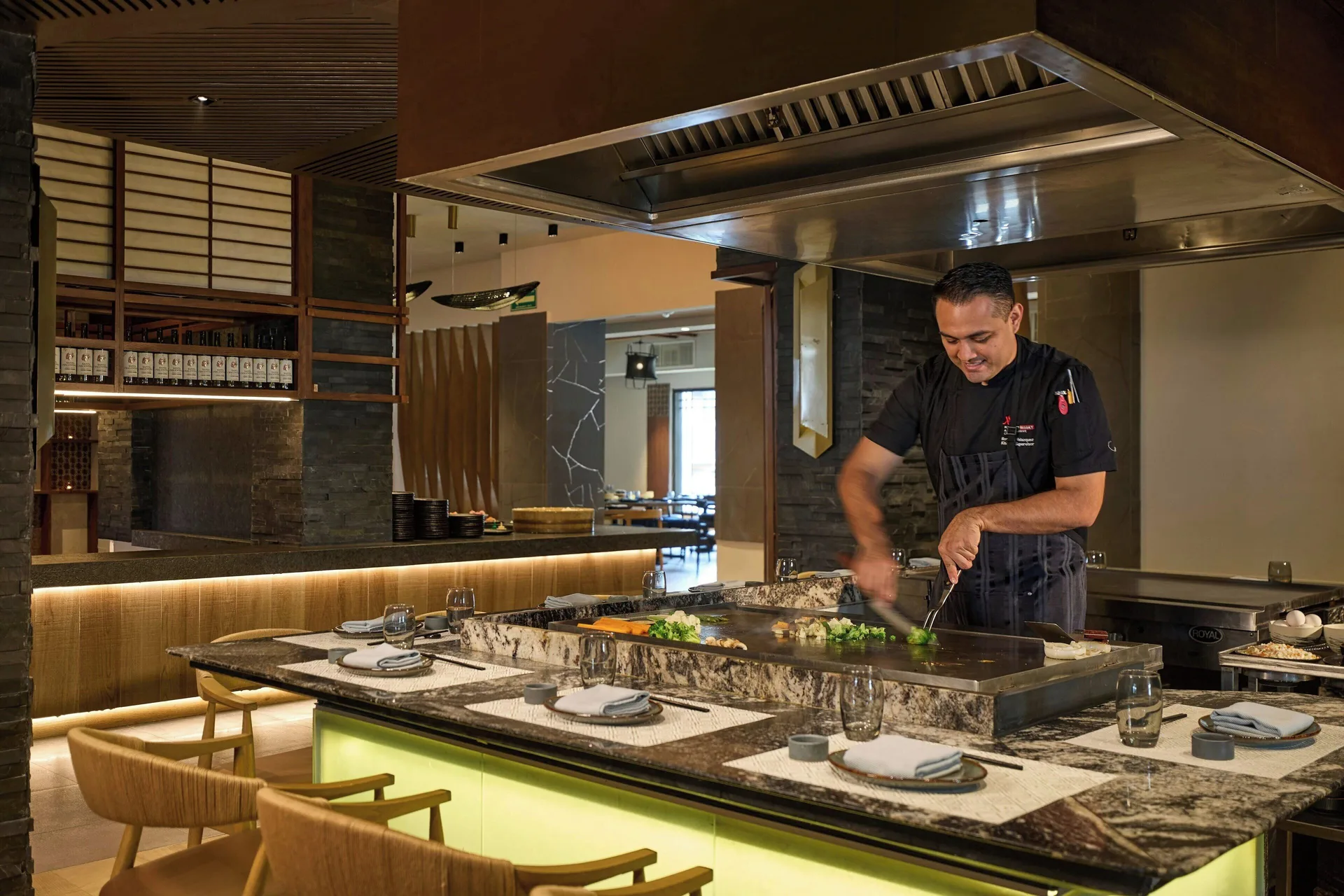 Chef cooking at a teppanyaki grill with counter seating at Marriott Cancun.