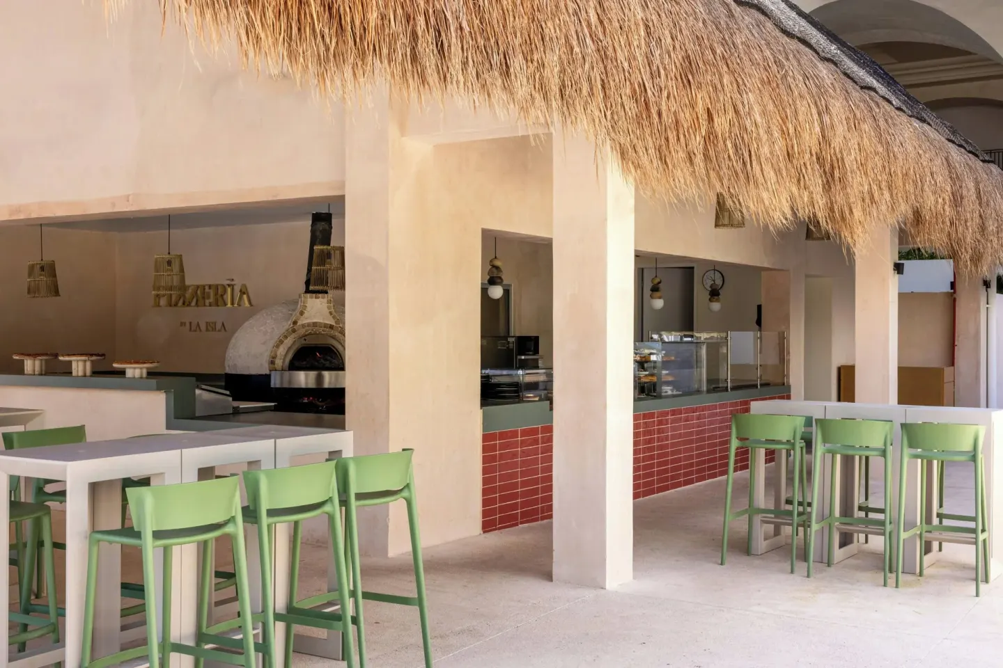 Pizzeria counter with green stools and a wood-fired oven at Marriott Cancun.