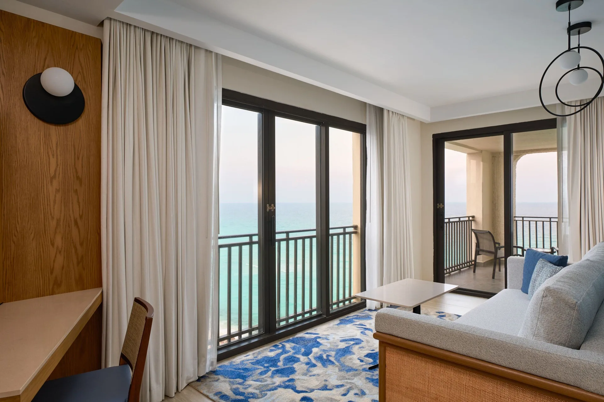 Caribbean Suite living area with sofa, desk, balcony, and ocean view at Marriott Cancun.