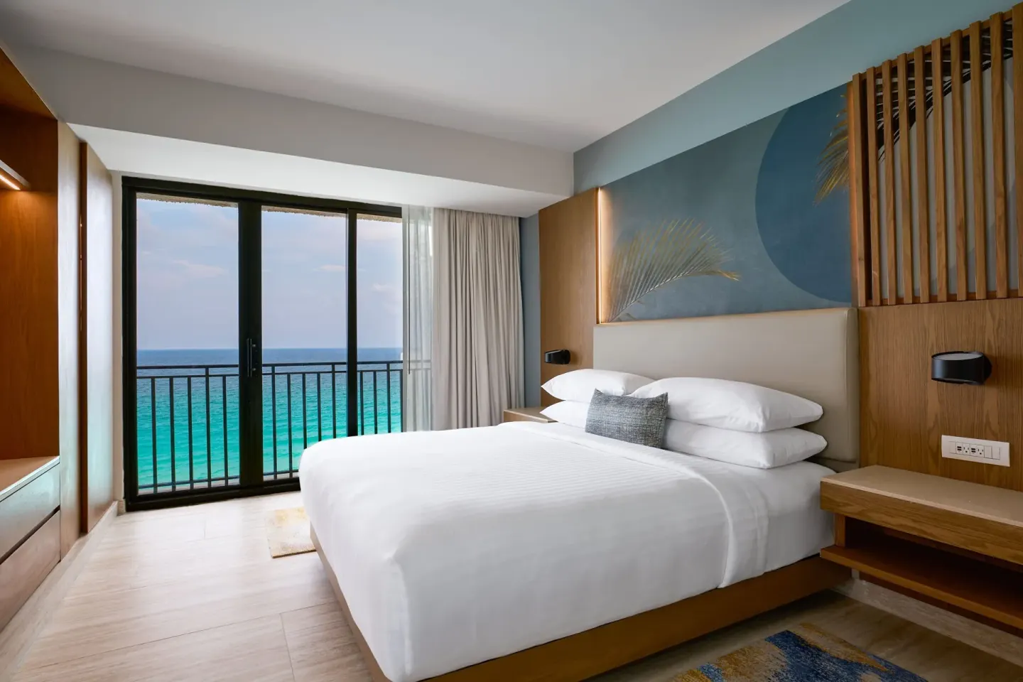Caribbean Suite bedroom with king bed, balcony doors, and ocean view at Marriott Cancun.
