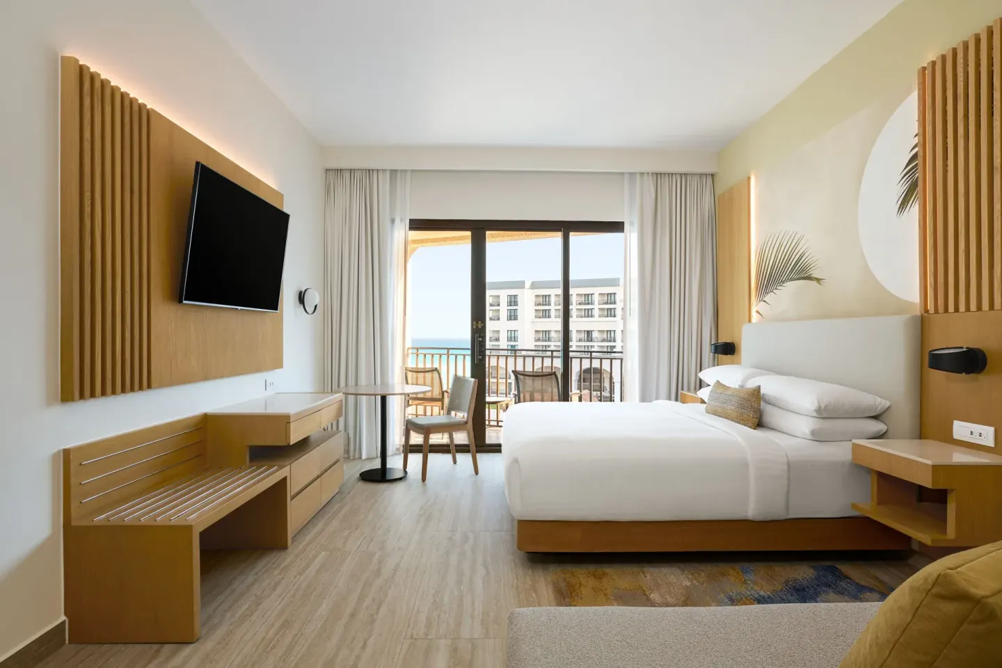 Ocean view guest room with king bed, balcony, desk, and TV at Marriott Cancun.