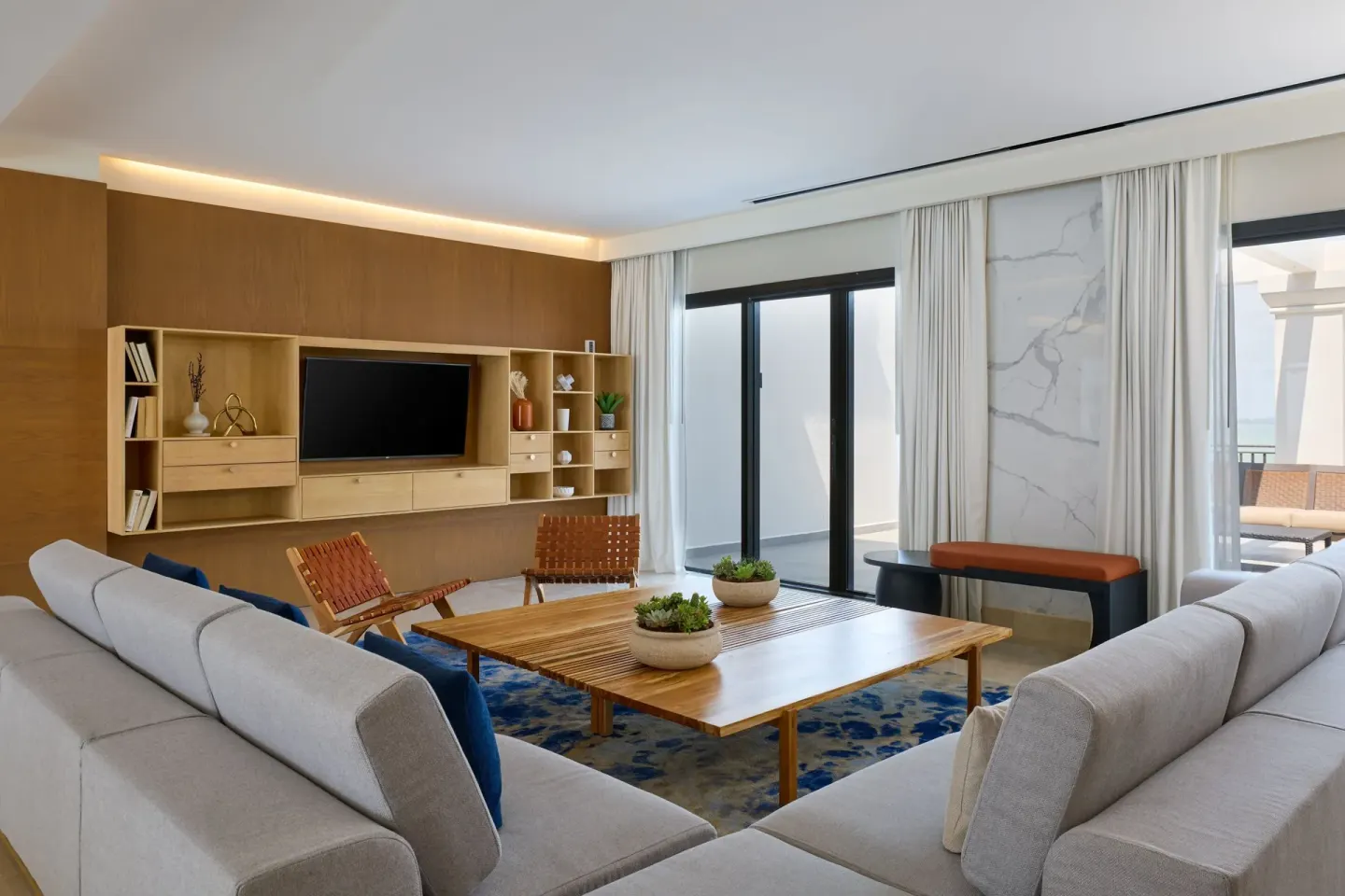 Presidential Suite living room with sofas, TV wall, and balcony doors at Marriott Cancun.
