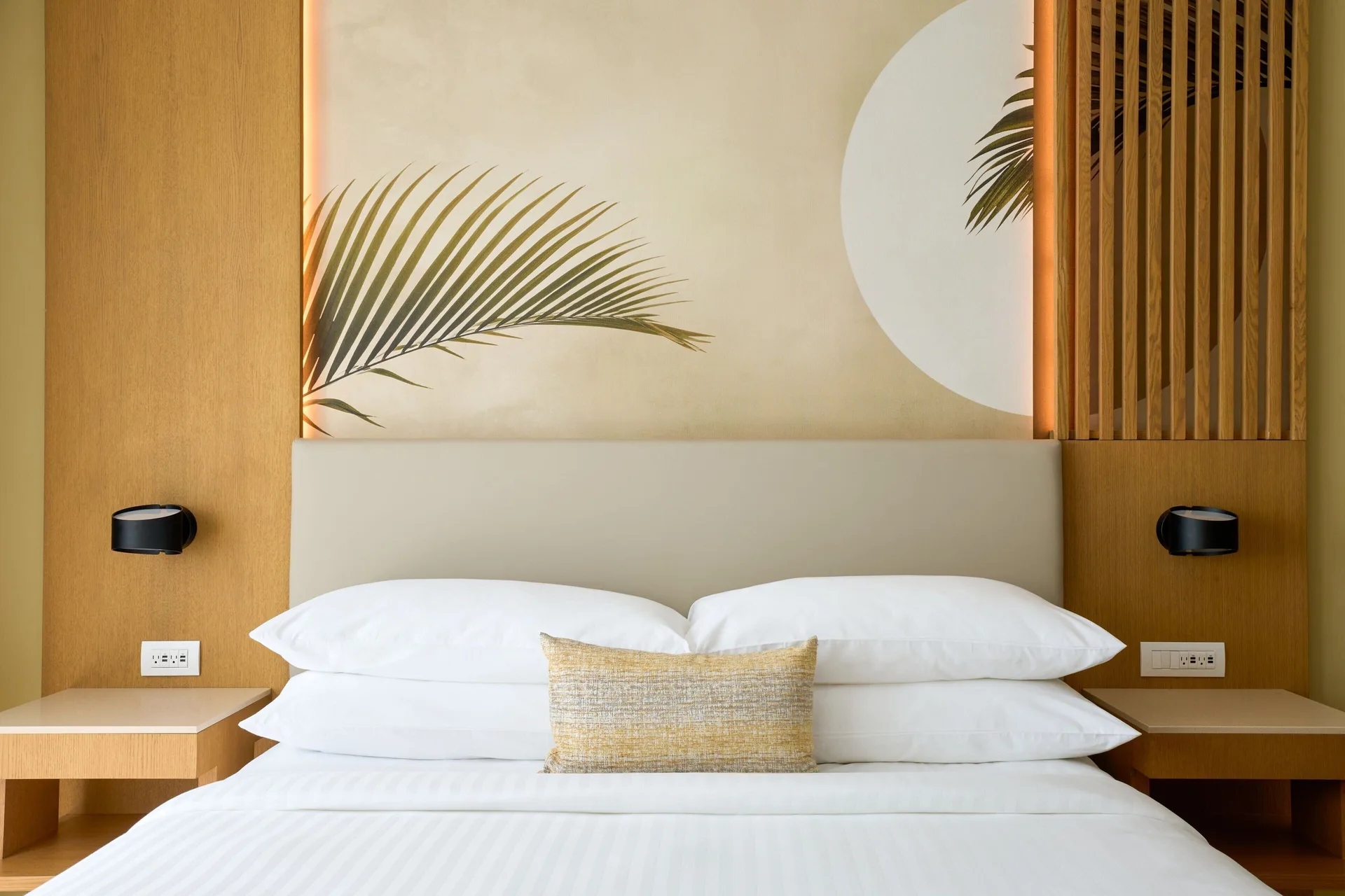 King bed with tropical wall art in a guest room at Marriott Cancun.
